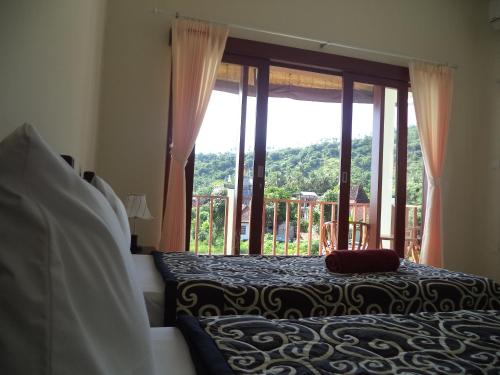 a bedroom with a bed and a large window at Gula Juruh Beach Front in Amed
