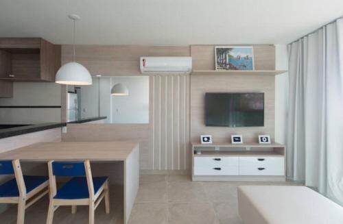 eine Küche mit einem Tisch und Stühlen sowie einem TV in der Unterkunft Orla Praia Grande in Arraial do Cabo