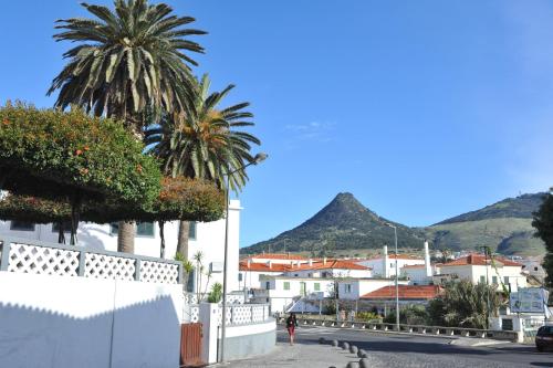 a person walking down a street with buildings and palm trees at 16 Porto Santo Apartments in Porto Santo