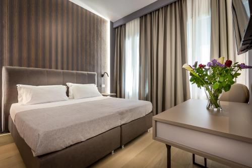 フィレンツェにあるBLU　ノッテ　ゲストハウスのベッドルーム1室(ベッド1台、花瓶付きのテーブル付)