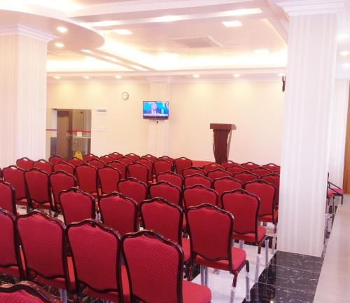 a lecture hall with red chairs and a podium at Hotel Grand United - Ahlone Branch in Yangon