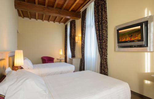 a hotel room with two beds and a flat screen tv at LHP Hotel Certaldo in Certaldo