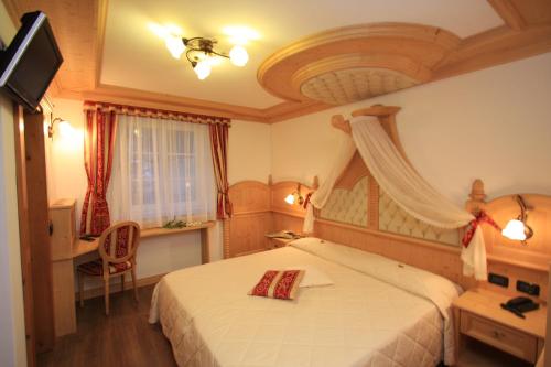 a bedroom with a bed and a desk and a television at Garnì Val de Costa in Canazei