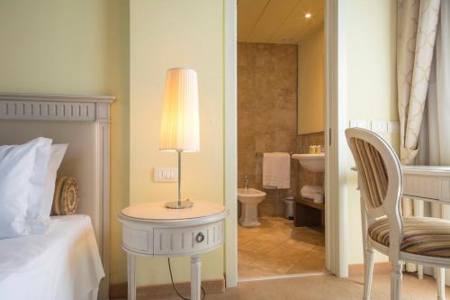 a bedroom with a bed and a lamp and a bathroom at LHP Hotel Certaldo in Certaldo