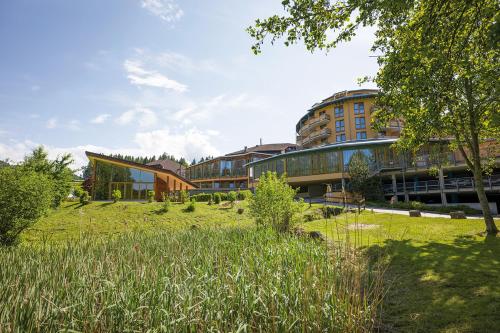 a building on a grassy field in front of a building at Vivea Gesundheitshotel Bad Häring in Bad Häring