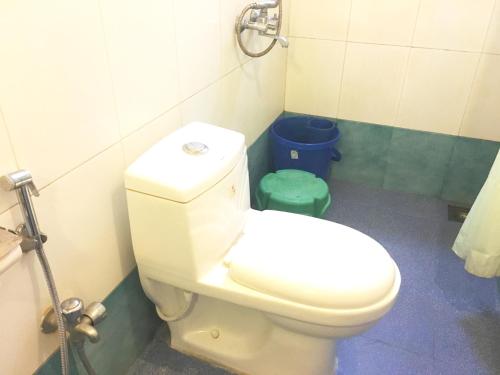 a bathroom with a white toilet and a blue trash can at 3bhk Duplex Villa With Pool In Candolim by GRStays in Candolim