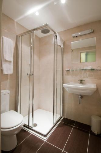 a bathroom with a shower and a toilet and a sink at Royal Eagle Hotel in London