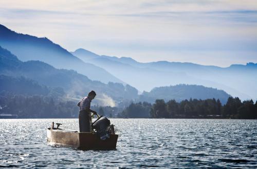 a man standing in a small boat on a lake at Garni Haus Sonnleitn - Adults only in Fuschl am See