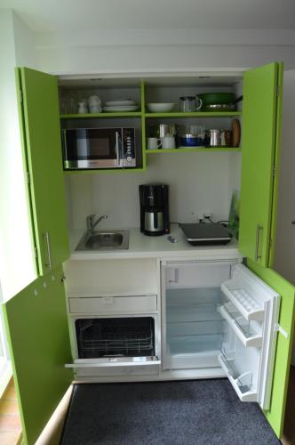 a small kitchen with green walls and white cabinets at Ferienapartments Cafe Stilbruch in Heimbach