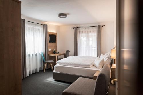 サン・マルティーノにあるGarni Grünauのベッドとデスクが備わるホテルルームです。