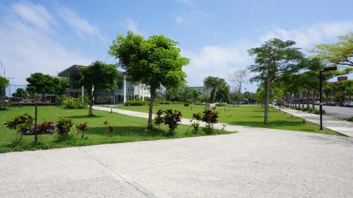 a park with trees and grass and a building at Warm Home in Taitung City