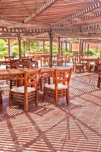 a group of wooden tables and chairs under a pavilion at Kefi Palmera Beach Resort El Sokhna - Family Only in Ain Sokhna