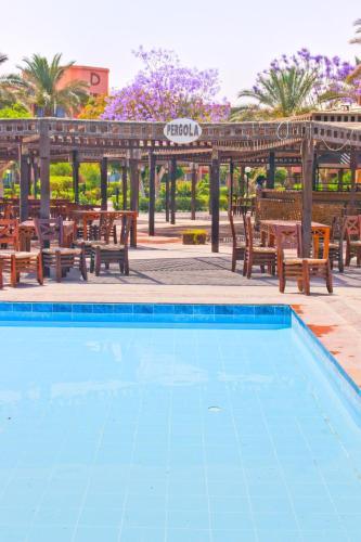 a swimming pool with chairs and a pergola at Kefi Palmera Beach Resort El Sokhna - Family Only in Ain Sokhna