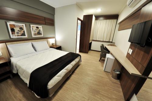 a hotel room with a bed and a desk at Klein Ville São Leopoldo in São Leopoldo