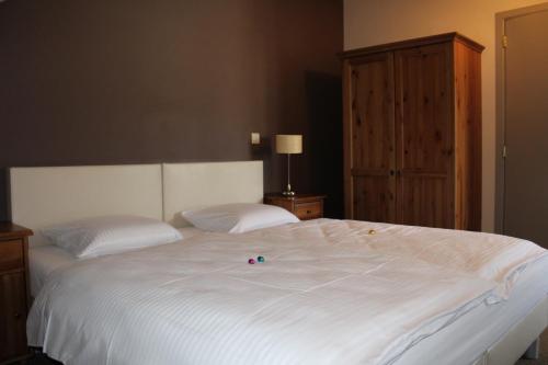 a large white bed with two pillows on top of it at B&B De Vroling in Wellen