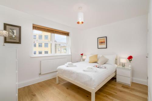 a white bedroom with a bed and a window at Sunny 2BR apt in the heart of Vauxhall, by subway in London