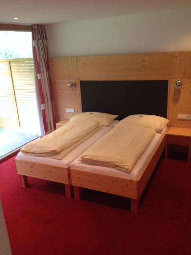 a bedroom with two beds with a wooden headboard at Apart Sportiva in Klösterle am Arlberg