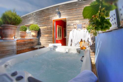 a bathroom with a tub with potted plants in it at Logis Au Canard Gourmand in Samatan