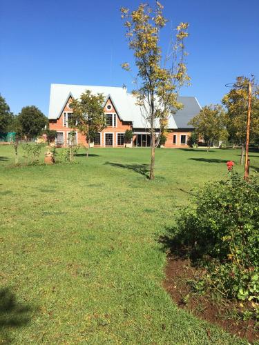 a house in a field with a tree in the yard at Millstream Inn guest house in Skeerpoort