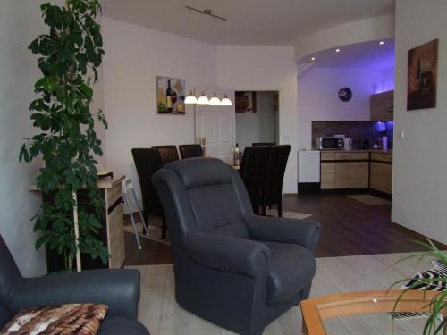 a living room with two chairs and a kitchen at Korzó Apartman in Kőszeg