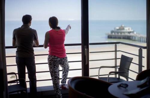 two people looking out of a window at the ocean at Hotel Riant-Séjour by WP Hotels in Blankenberge