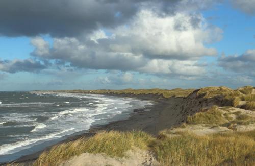 a beach with rocks and the ocean on a cloudy day at Hostel Agger Vandrerhjem in Agger