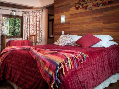 a bedroom with a large bed with a red blanket at Pousada Oliveri in Monte Verde