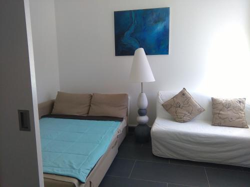 Cette chambre comprend un canapé, un lit et une lampe. dans l'établissement Résidence Robinson Standing Pieds dans l'eau, à Agay