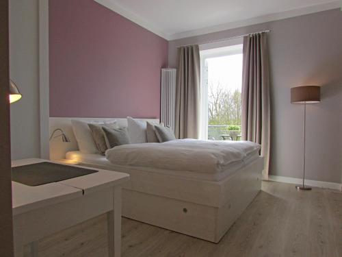 a bedroom with a white bed and a window at Gästehaus Muhl in Strukkamp auf Fehmarn