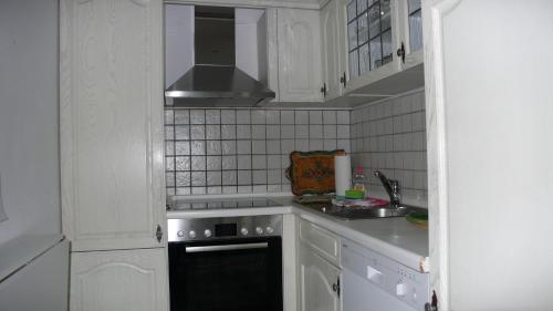 eine Küche mit weißen Schränken und einem Herd mit Backofen in der Unterkunft Apartment Xenia in Garmisch-Partenkirchen