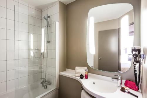 une salle de bain avec un lavabo, une douche et un miroir dans l'établissement ibis Paris Gare De L'Est TGV, à Paris