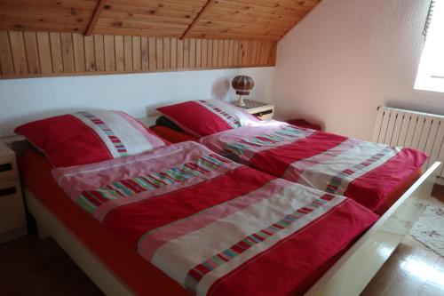 a bed with a red and white blanket on it at Pokoje Herta - Domek letniskowy in Stawiguda