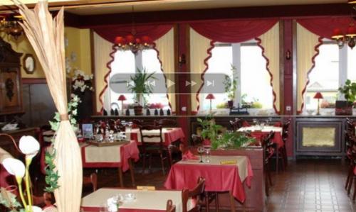a restaurant with tables and chairs with red table cloth at La Table Alsacienne in Farébersviller