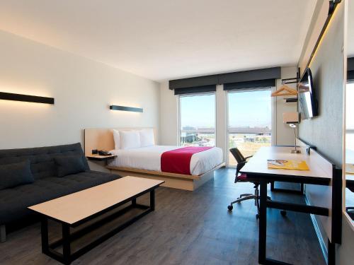 a hotel room with a bed and a couch at City Express by Marriott Santiago Aeropuerto in Santiago