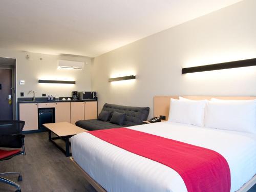 a hotel room with a large bed and a couch at City Express by Marriott Santiago Aeropuerto in Santiago
