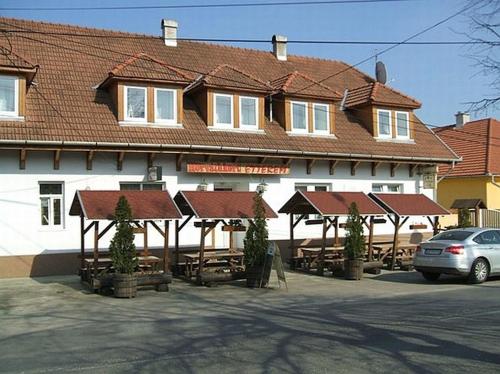 a building with tables and umbrellas in front of it at Horváthkert Panzió és Étterem in Bogács