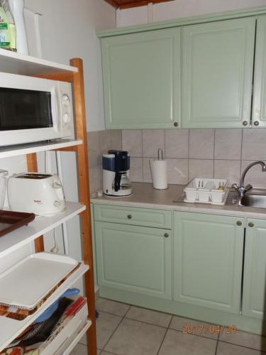 a kitchen with green cabinets and a microwave at Hipságh Vendégház in Hegykő