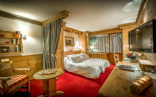 a living room with a couch and a tv at Hotel & Spa Le Dahu in Morzine