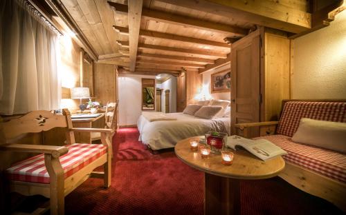 a hotel room with a bed and a table and chairs at Hotel & Spa Le Dahu in Morzine