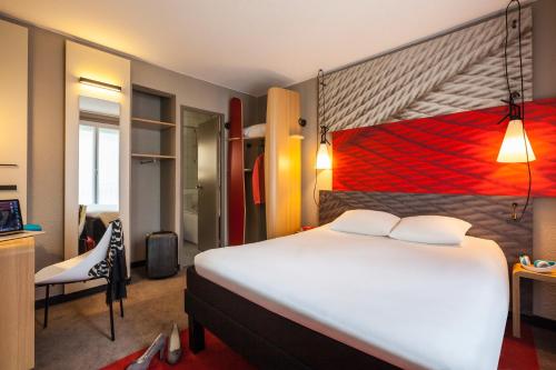 a bedroom with a large white bed and a chair at ibis Paris Gare De L'Est TGV in Paris