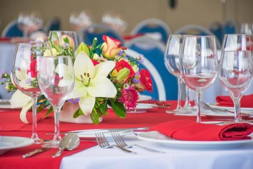 a table with wine glasses and a vase of flowers at Hotel Stadium Leon in León