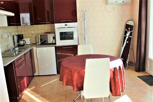a kitchen with a table and white chairs in it at LOCATIONS RIVES DE SEUGNE - Claveau in Jonzac