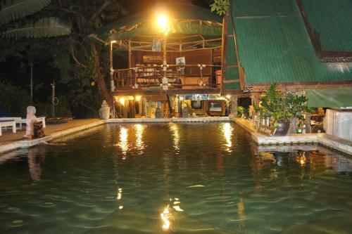 a swimming pool at night with a building in the background at Tropical Garden Bungalow in Phi Phi Don