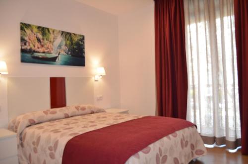 a hotel room with a bed with red curtains at ApartSuits Tarragona Rambla Nova 24 in Tarragona