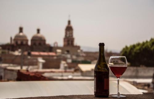 a bottle of wine next to a glass of wine at Hotel Casa Aurora in Quer&eacute;taro
