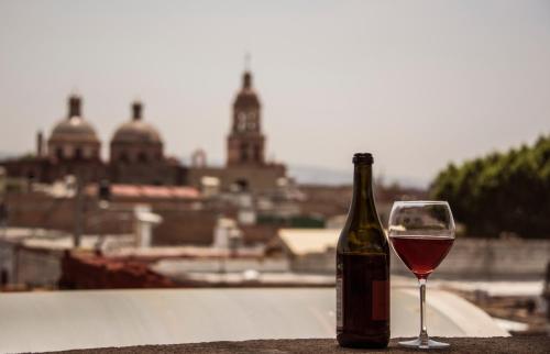 una botella de vino junto a una copa de vino en Hotel Casa Aurora en Querétaro