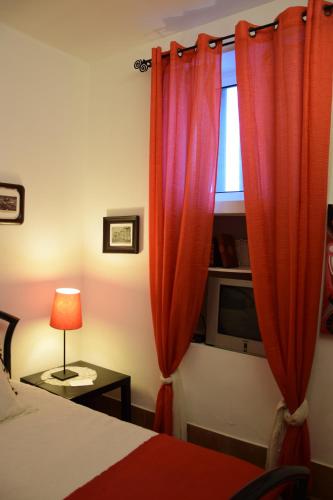 a bedroom with a bed and a window with red curtains at Casa da Paleta in Castelo de Vide