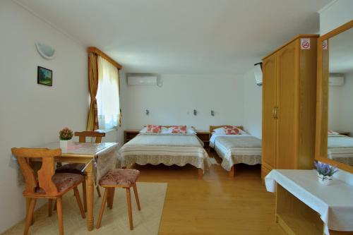 a room with two beds and a table and chairs at Guest House Ljubo & Ana in Rastovača