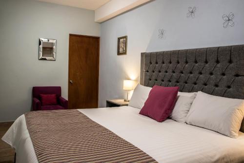 a bedroom with a large bed with purple pillows at Hotel Casa Aurora in Querétaro