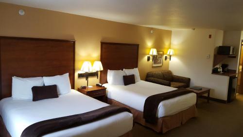 a hotel room with two beds and a chair at Expressway Suites Fargo in Fargo